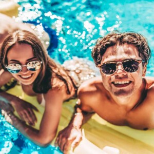girl and guy floating in pool smiling